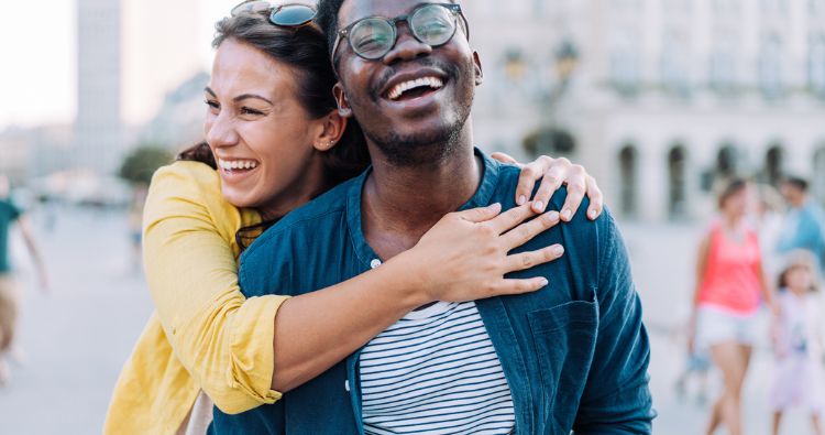 A young couple embraces while walking in the city.