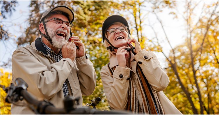 A retirement-aged couple puts on helmets for a bike ride.