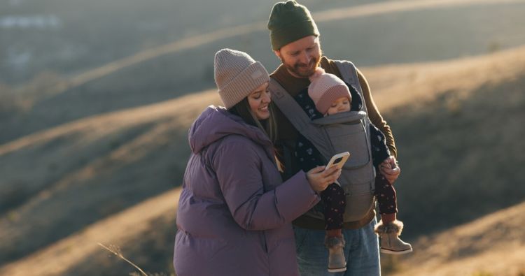 A young mother and father take a hike with their baby.