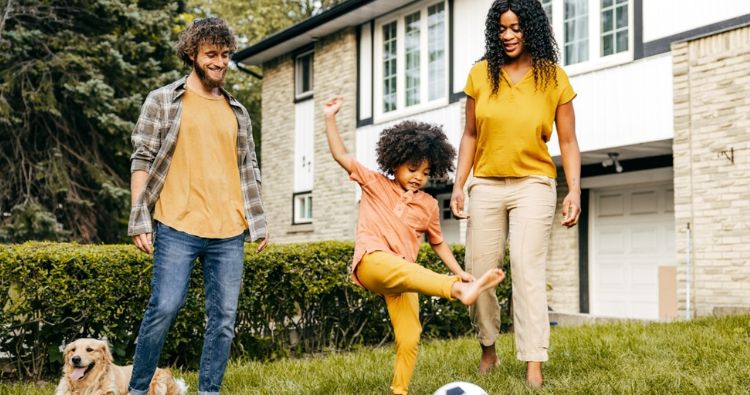 A family play soccer in their front yard.