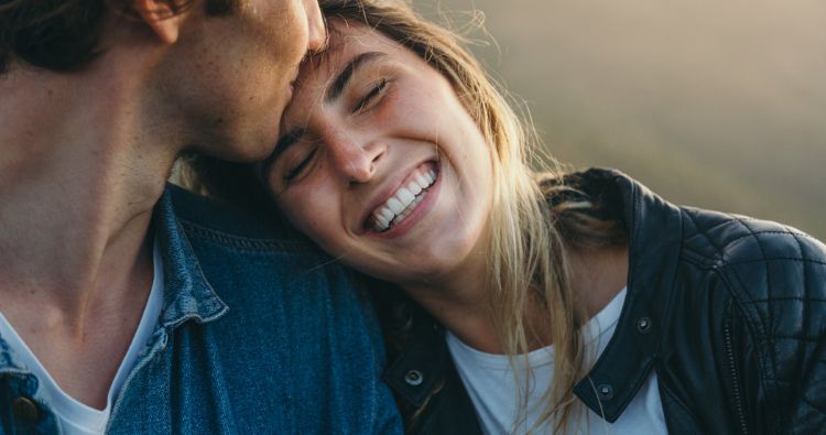 A young couple laugh while embracing.