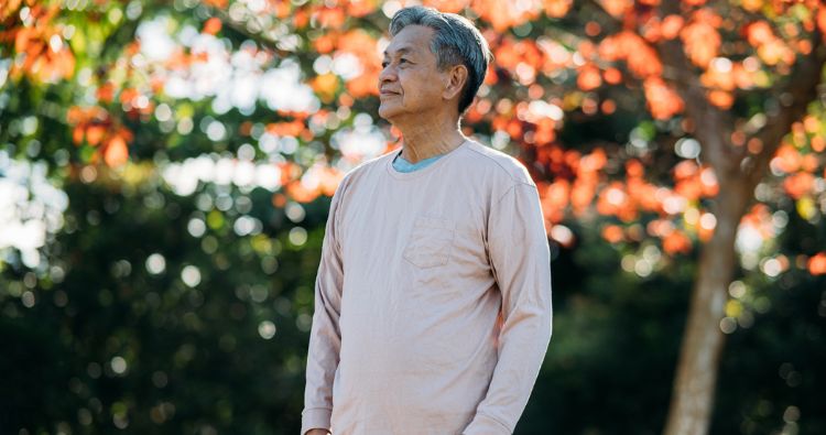 A retirement-aged man talk a autumn walk through the park.