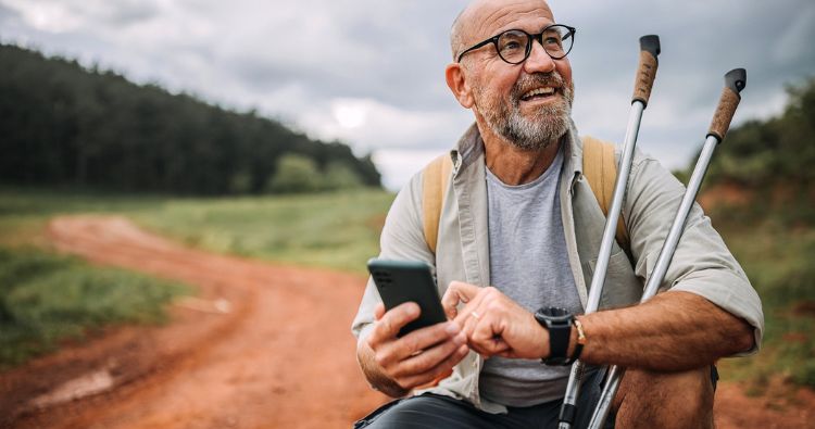 A man checks his phone while hiking a trail