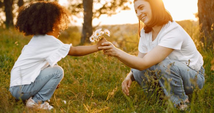 A woman give her daughter some flowers she has picked