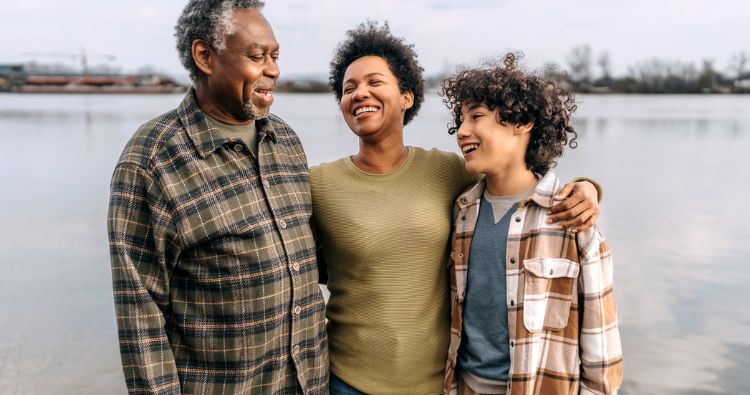 A multi-generational family embrace while outside.