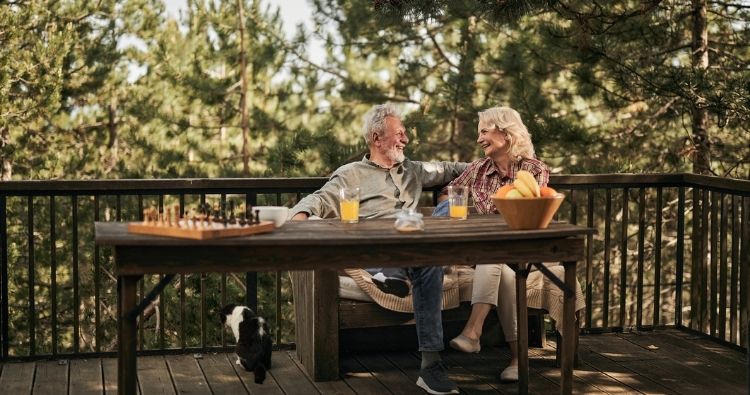 A retirement aged couple sit on their back deck enjoying quiet time together.