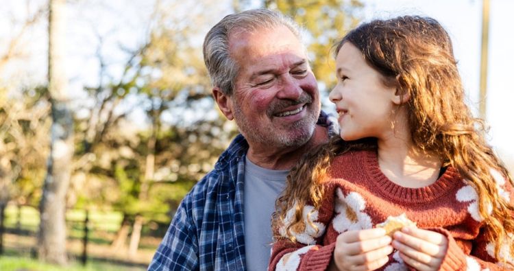 A grandfather smiles at his granddaughter